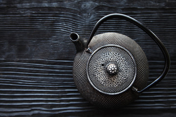 Close up black metall tea pot on a black wooden background