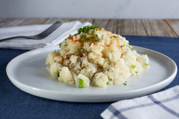 A view of a plate of potato salad, in a restaurant or kitchen setting.