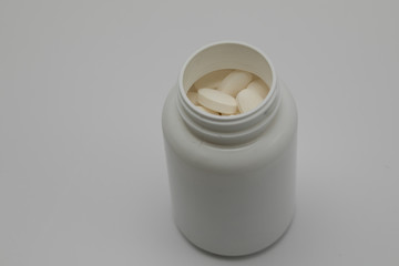 White round tablets covered with a cover are scattered from a plastic can with them.