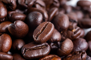 A macro closeup view of a mound of dark roasted coffee beans.
