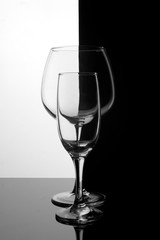 Two glass glasses one behind the other on a black and white background. Geometric symmetry.