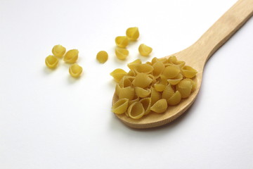 Shell pasta in a wooden spoon on a white background