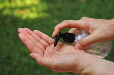 Closeup of woman's hand using  alcohol gel from bottle for cleaning her hand to prevent corona...