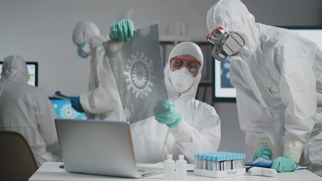 Researchers in coveralls study covid-19 virus cell