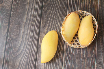 Yellow mango in basket on wood table. Top view. Copy space. Zero Waste