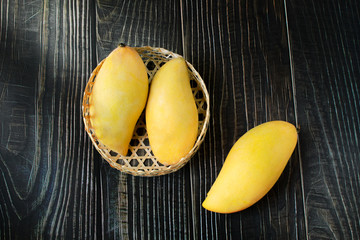 Yellow mango in basket on wood table. Top view. Copy space. Zero Waste
