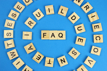 The word faq is made of wooden letters on a blue background