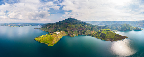 Aerial: lake Toba and Samosir Island view from above Sumatra Indonesia. Huge volcanic caldera covered by water, traditional Batak villages, green rice paddies, equatorial forest.