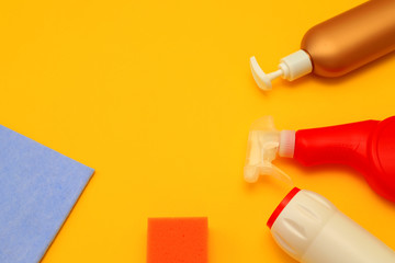 Plastic containers, napkins, sponges on a yellow background for the cleaning the kitchen, bathroom. Detergents, cleaning bottles, various sizes, colors.