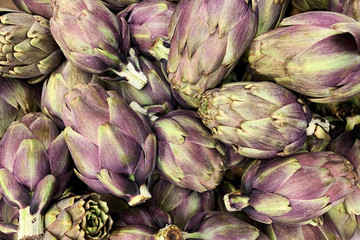 Obraz premium Heap of ripe fresh artichokes in the market counter. Vegetables background texture. Advertisement backdrop