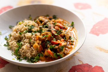 close up of asian vegan healthy homemade curry dish with rice, parsley, aubergine, carrots and mushrooms on table cloth with soft natural light