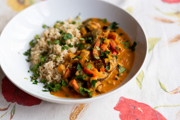 close up of asian vegan healthy homemade curry dish with rice, parsley, aubergine, carrots and mushrooms on table cloth with soft natural light