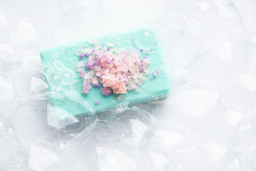 Blue soap with  pink sea salt in soap bubbles, on a white  background, top view