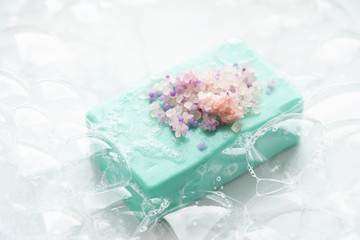 Blue soap with  pink sea salt in soap bubbles, on a white  background, top view