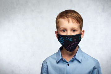 A worried child wear DIY protective face mask to prevent infection or pollution. COVID-19 protection concept.