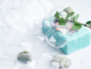 Blue soap with  pink sea salt in soap bubbles, on a white  background, top view