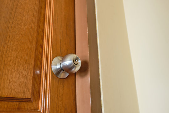 Silver Doorknob On Closed Wooden Door.