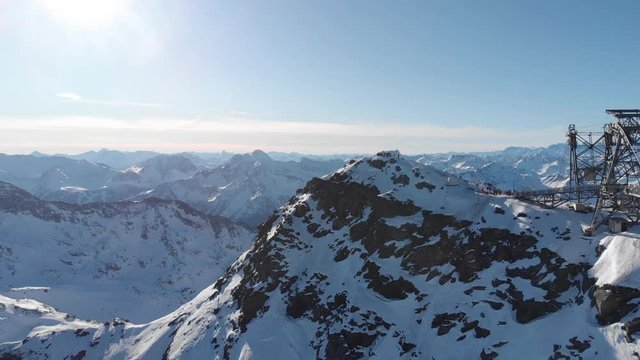 Orbit aerial over winter snowy mountain top ski tracks resort with skier people skiing. Drone video footage of Gondola lift cabin of ski-lift in the ski resort Val Thorens.