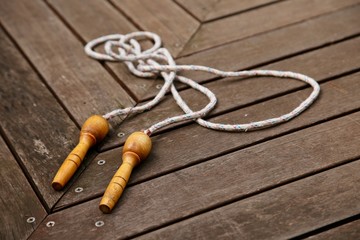 An old skipping rope on a wooden deck. Exercising at home concept image.  