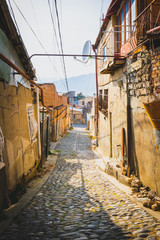 Pathway of traditional narrow georgian roads with rocky ground and old stylish living buildings without people. Concept of safe neighborhood. Background vintage image. 2020