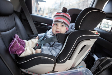 Child safety seat with smiling infant child is on back seat of car, kid eight month old