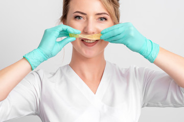 Beautician holding liquid sugar paste like mustache, close up.