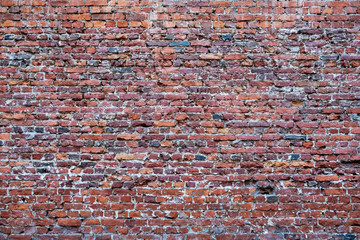 a large old wall of red and dark blue bricks. rough surface texture