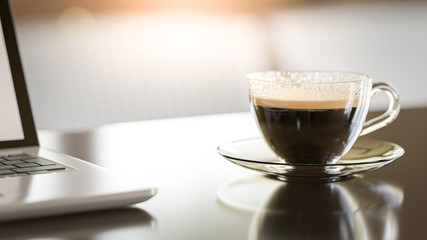3D Rendering. Coffee cup and laptop on table.