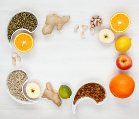 Orange, ginger, garlic, lime, lemon, raisins, sunflower seeds, pumpkin seeds are spread out on a white background, space for text. Fighting viruses and colds with natural immune organic products