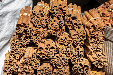 Bunches of cinnamon sticks tied together outdoor on sunlight at market spice store