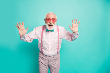 Naklejka premium Hey-hey its me. Portrait of positive cheerful old man true hipster raise hands greet his retired friends family scream wear good looking outfit isolated over green color background