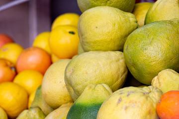 Pile of pomelo fruits at food market, selective focus on foreground on pomelo fruit, blurred citrus fruit on background