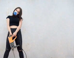  sexy girl stands in a mask with a puncher in her hands. Repair. Girl Builder. Protection from the...