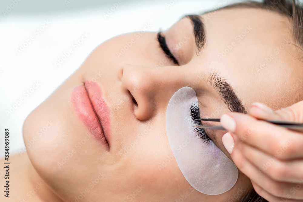 Wall mural Woman receiving eyelash extension procedure close up.