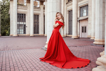 Beautiful blonde girl in a red long dress on a background of architecture, columns 
