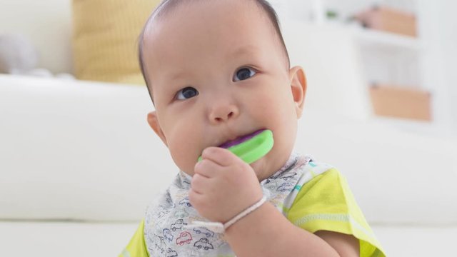 Little asian baby biting plastic teether 