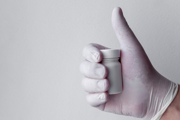Male hand in medical gloves holds a plastic jar of pills. Virus