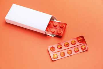 Box with pills on color background