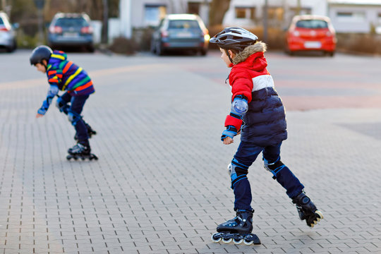 Two Little Kids Boys Skating With Rollers In The City. Happy Children, Siblings And Best Friends In Protection Safety Clothes. Active Schoolboys Making Sports And Learning To Skate On Inline Skater.