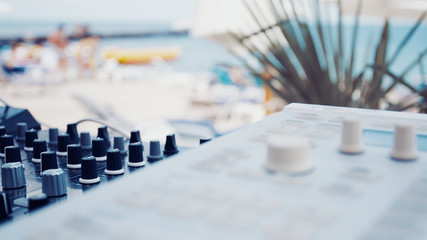 Summer beach music party background. Dj equipment closeup on blurred beach background