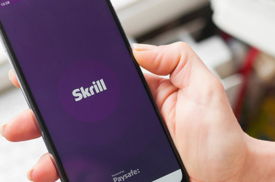 Woman uses the Skrill app on her smartphone. Skrill is a service that allows you to send and receive money worldwide.