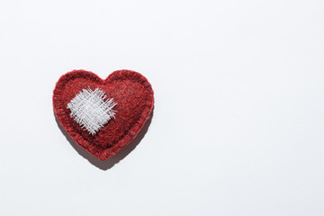 red textured heart on a white background with a bandage, the concept of recovery
