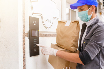 Courier in protective mask and medical gloves delivers takeaway food. Delivery service under...