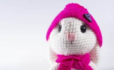 Cute handmade white rabbit in a pink hat wishes you a happy Easter! White background, frame for text, close up