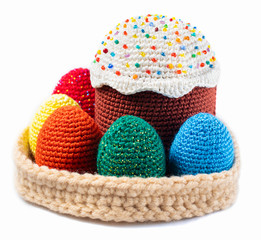Happy Easter, close-up of a handmade knitted cake in a basket with yellow, orange, red, blue and green Easter chicken eggs isolated on a white background, front view