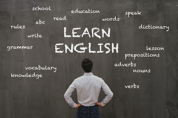 learn english concept, business man looking at word cloud on chalk board