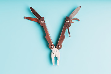 The multitool multi-function tool hovers on a blue background. The concept of an expanded multi-tool with free space.