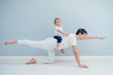 A sports man is engaged in fitness and yoga with a baby at home