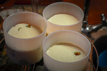 Cooking at home young cheese brynza with green olives in cheese molds. Homemade, handmade at home in the kitchen 