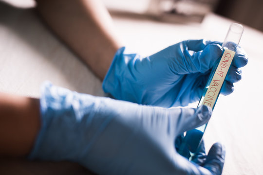 Conceptual image of a doctor holding and looking at a tube of coronavirus (COVID-19) vaccine.